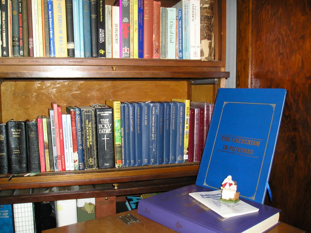 Catholic homeschool books on shelf with more books on desk.